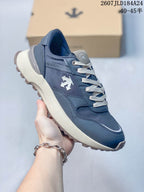 Three-quarter side view of the navy DESCENTE sneaker showing the logo, cream midsole and brown-toned outsole.
