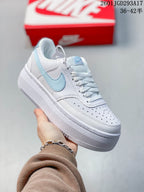 Angled side view of the white and light blue Nike sneaker with perforated toe and raised sole.