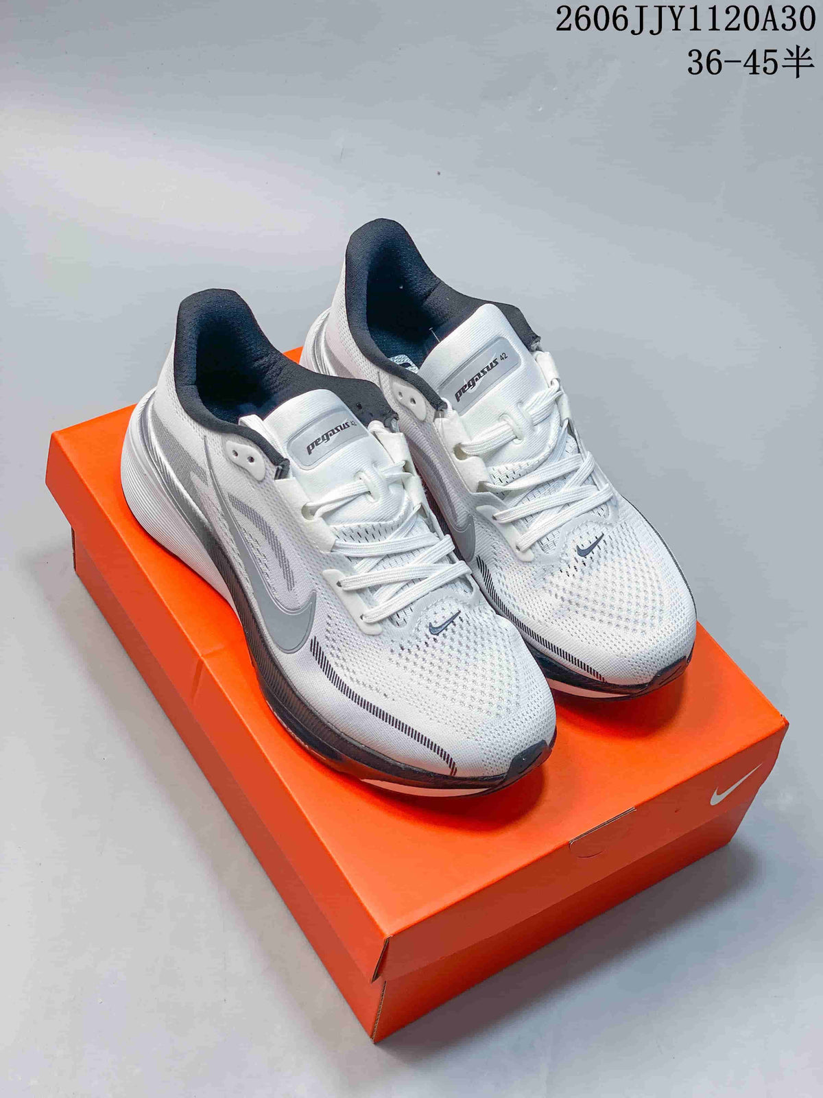 Pair of white and gray Nike Pegasus 42 shoes displayed on an orange box