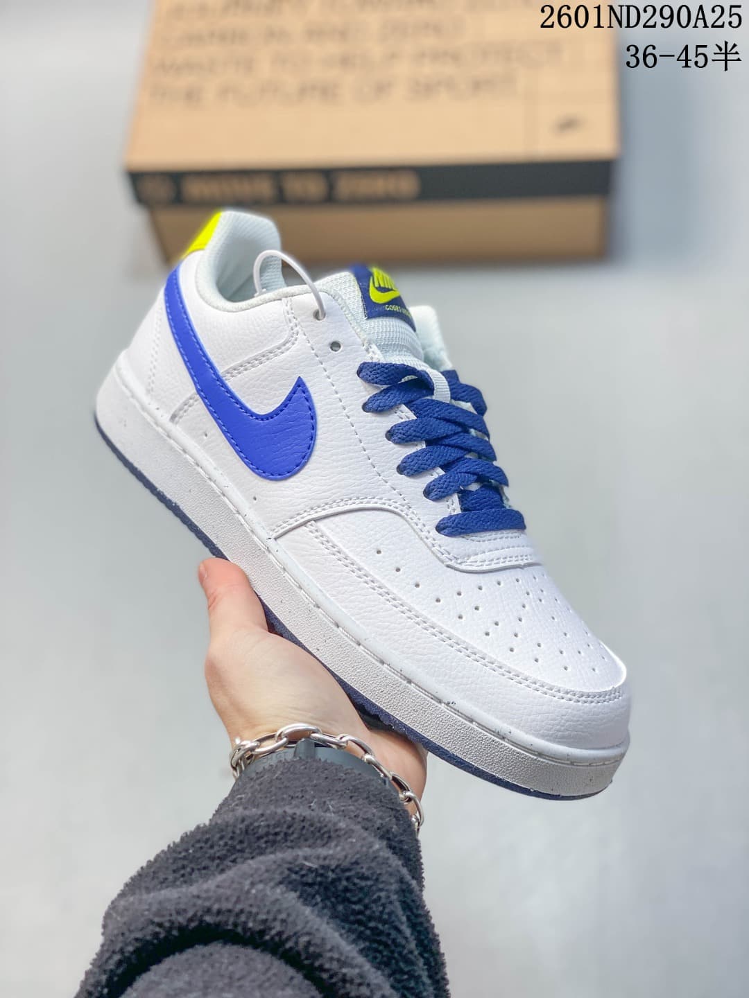 Angled side view showing the white upper, blue laces and Swoosh, perforated toe box, and blue outsole.