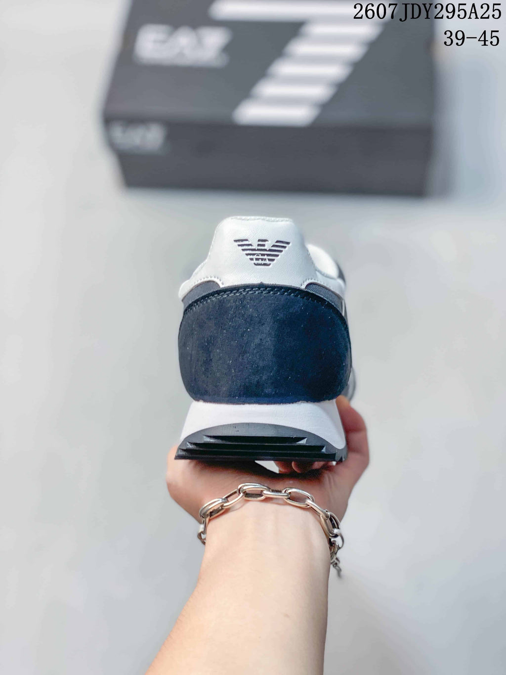 Rear view of the navy and white sneaker showing the padded heel area, EA7 logo, white midsole, and dark textured outsole.