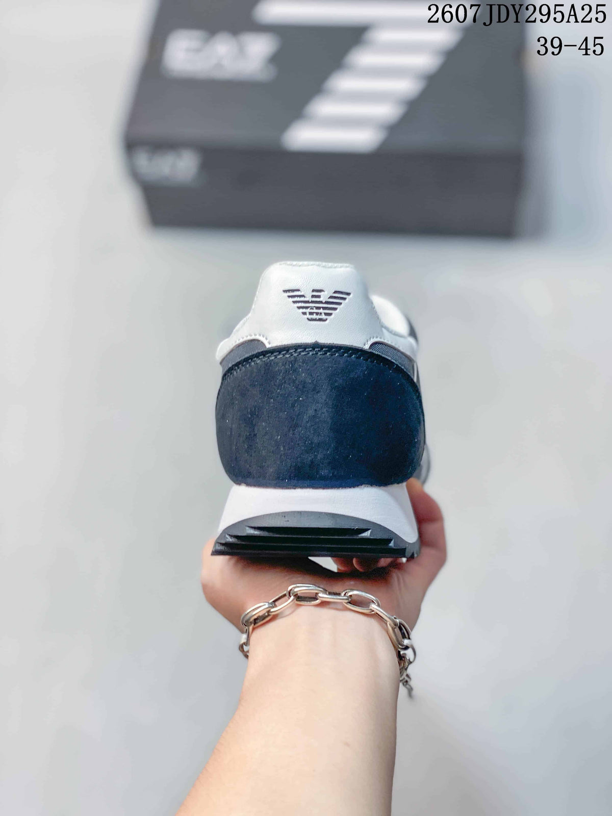 Rear view of the navy and white sneaker showing the padded heel area, EA7 logo, white midsole, and dark textured outsole.
