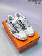 Pair of white low-top sneakers with dark indigo and pale green monogram-style panels and patterned laces on an orange box.