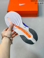 Underside view of the shoe showing a white and black segmented rubber outsole with an orange central accent.