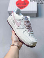 Angled side view highlighting the white low-top construction, pink accents, perforated toe and contrasting outsole.