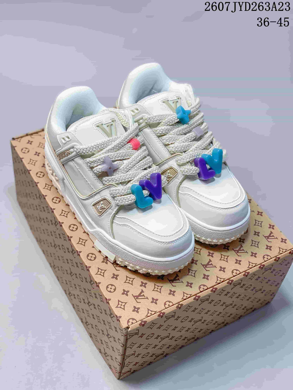 Pair of white Louis Vuitton Trainer Maxi sneakers with multicolor lace charms displayed on a patterned presentation box; image text shows code 2607JYD263A23 and size range 36–45.