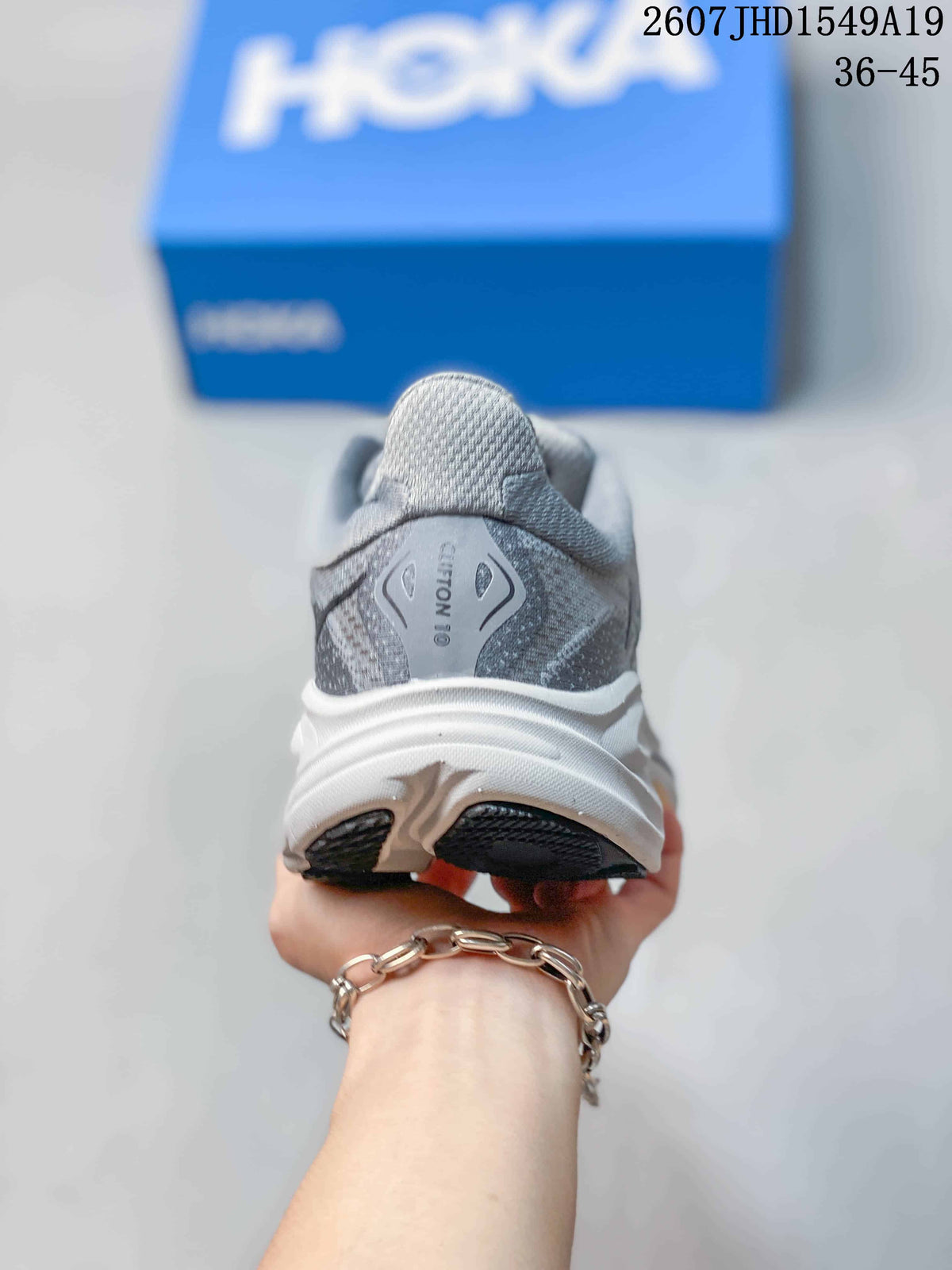 Rear view of a gray sneaker showing the padded heel, sculpted white midsole, and Clifton 10 marking.