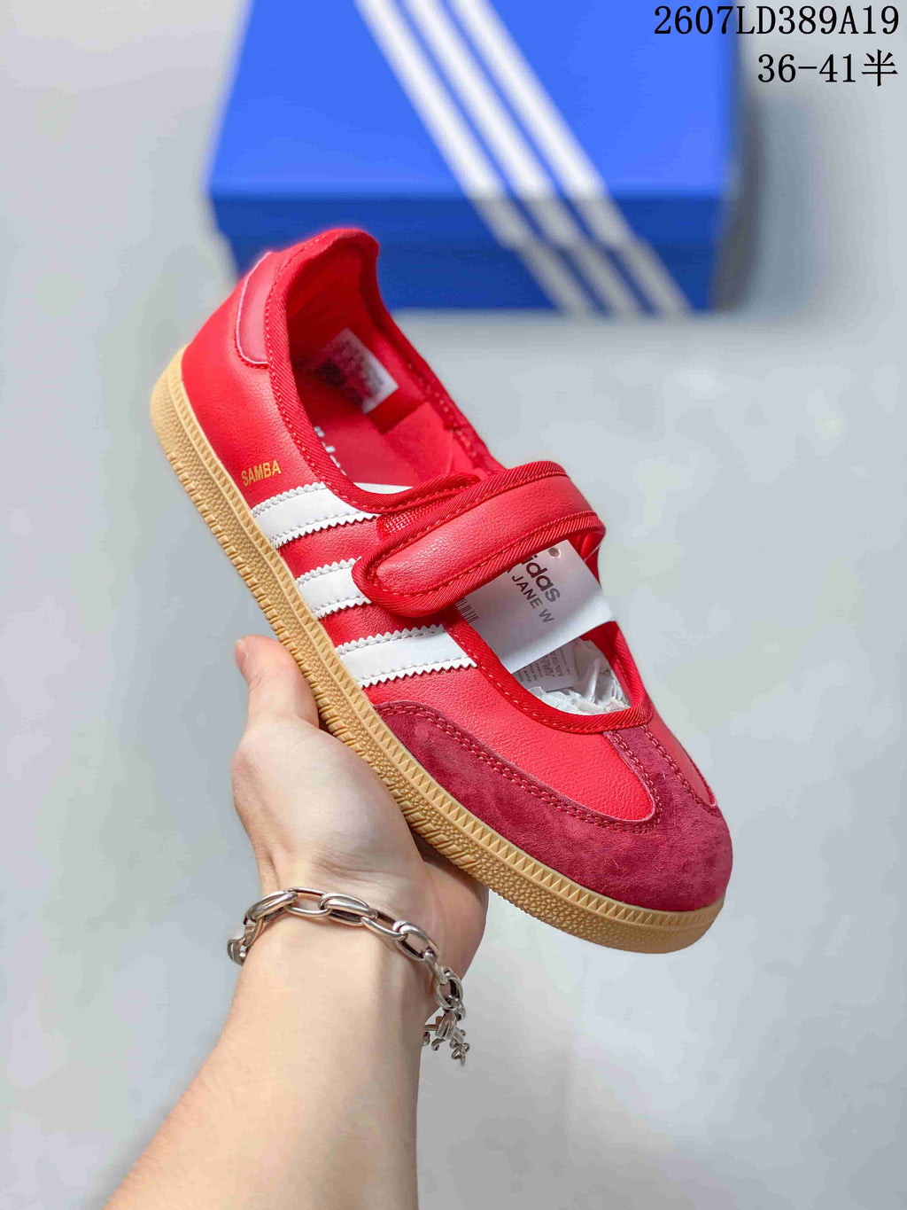 Angled view of the red and white Samba Jane sneaker showing the strap, white stripes, contrasting toe panel, and gum sole.