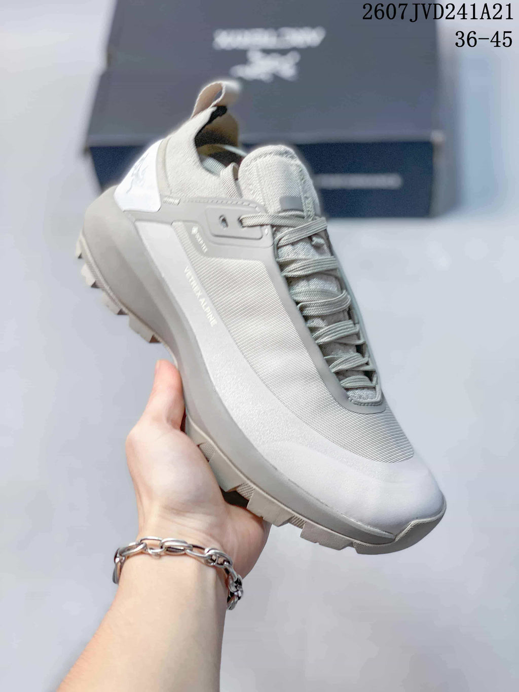 Angled side view showing the lace-up trail sneaker, heel pull tab, side panels, and outsole.