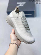 Angled side view showing the lace-up trail sneaker, heel pull tab, side panels, and outsole.