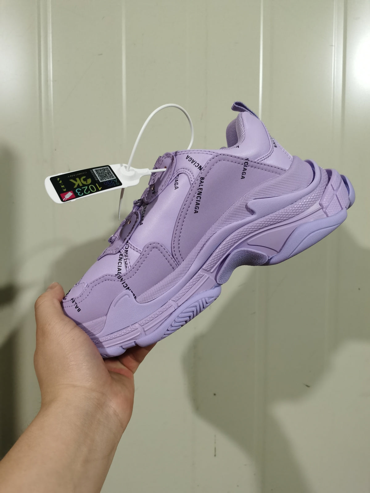 Rear three-quarter view of the purple Balenciaga Triple S sneaker with a hanging tag.