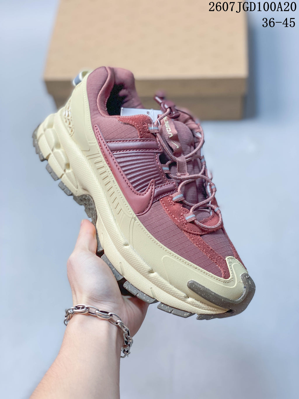 Three-quarter side view showing the burgundy and cream color blocking, layered upper, cushioned midsole, and rugged outsole.