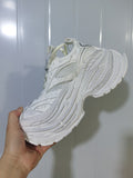 Close-up side view of an all-white platform sneaker showing mesh panels, layered overlays, laces, and a sculpted outsole.