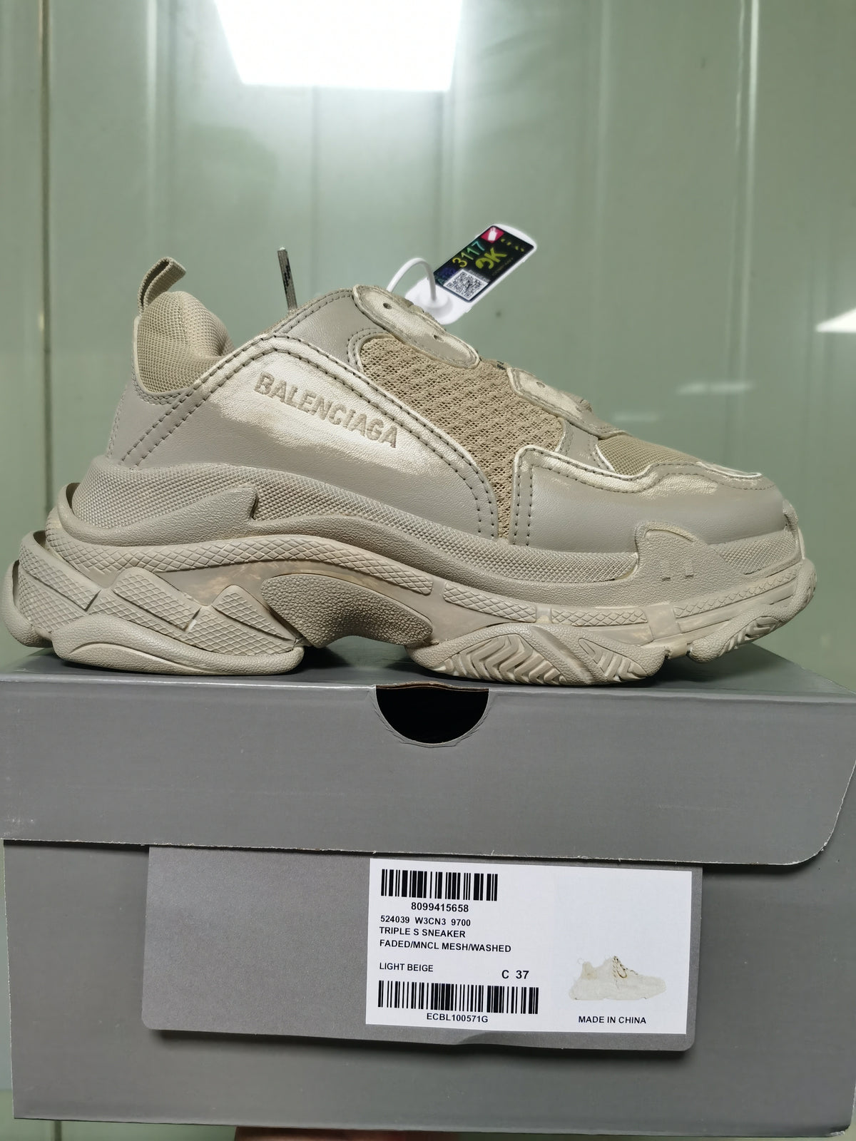Light beige Balenciaga Triple S sneaker displayed on its box; the label identifies the style as 524039 W3CN3 9700 and shows size C 37.