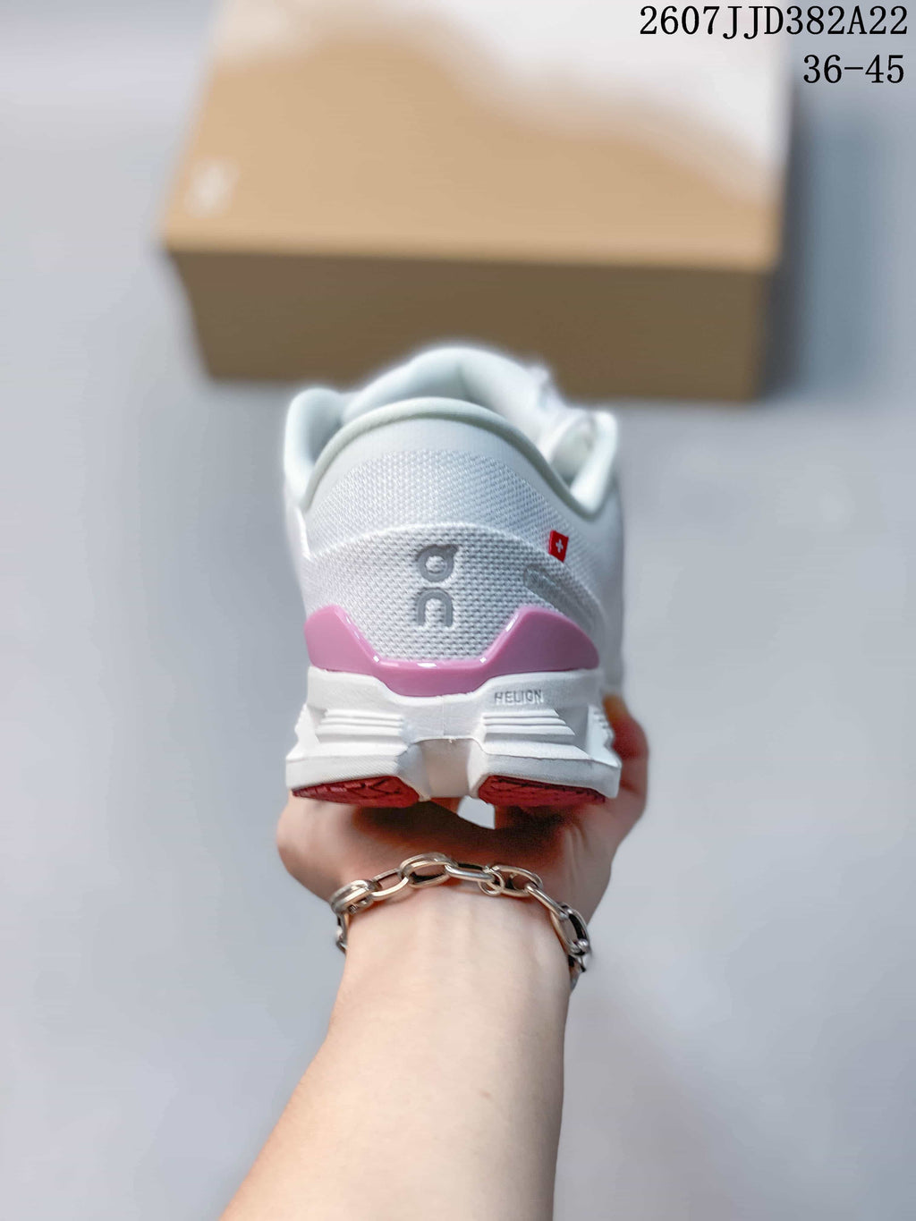 Rear view of the white sneaker showing the padded heel, pink heel accent, On branding, and segmented outsole.