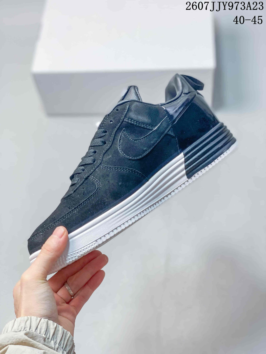 Side profile of the black low-top sneaker showing the Nike Swoosh, layered panels, ribbed heel detail, and white outsole; image text shows product code 2607JJY973A23 and size range 40–45.