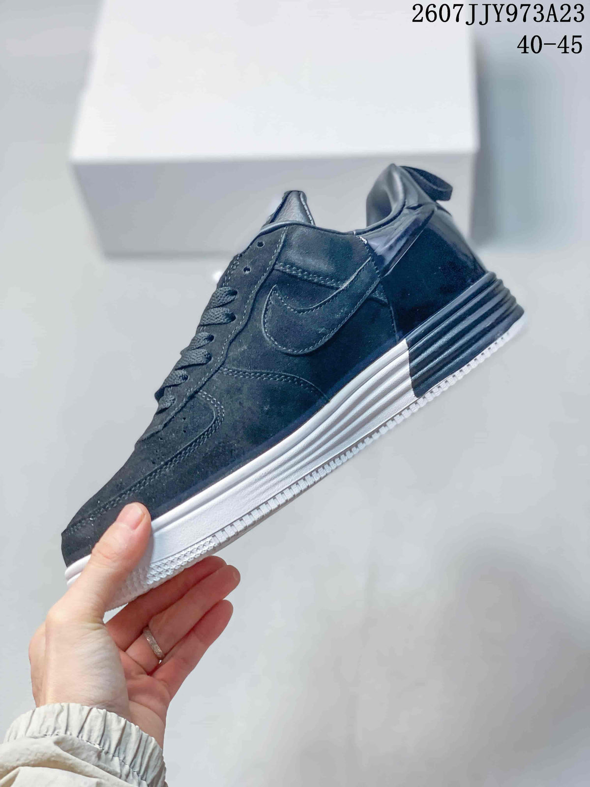 Side profile of the black low-top sneaker showing the Nike Swoosh, layered panels, ribbed heel detail, and white outsole; image text shows product code 2607JJY973A23 and size range 40–45.