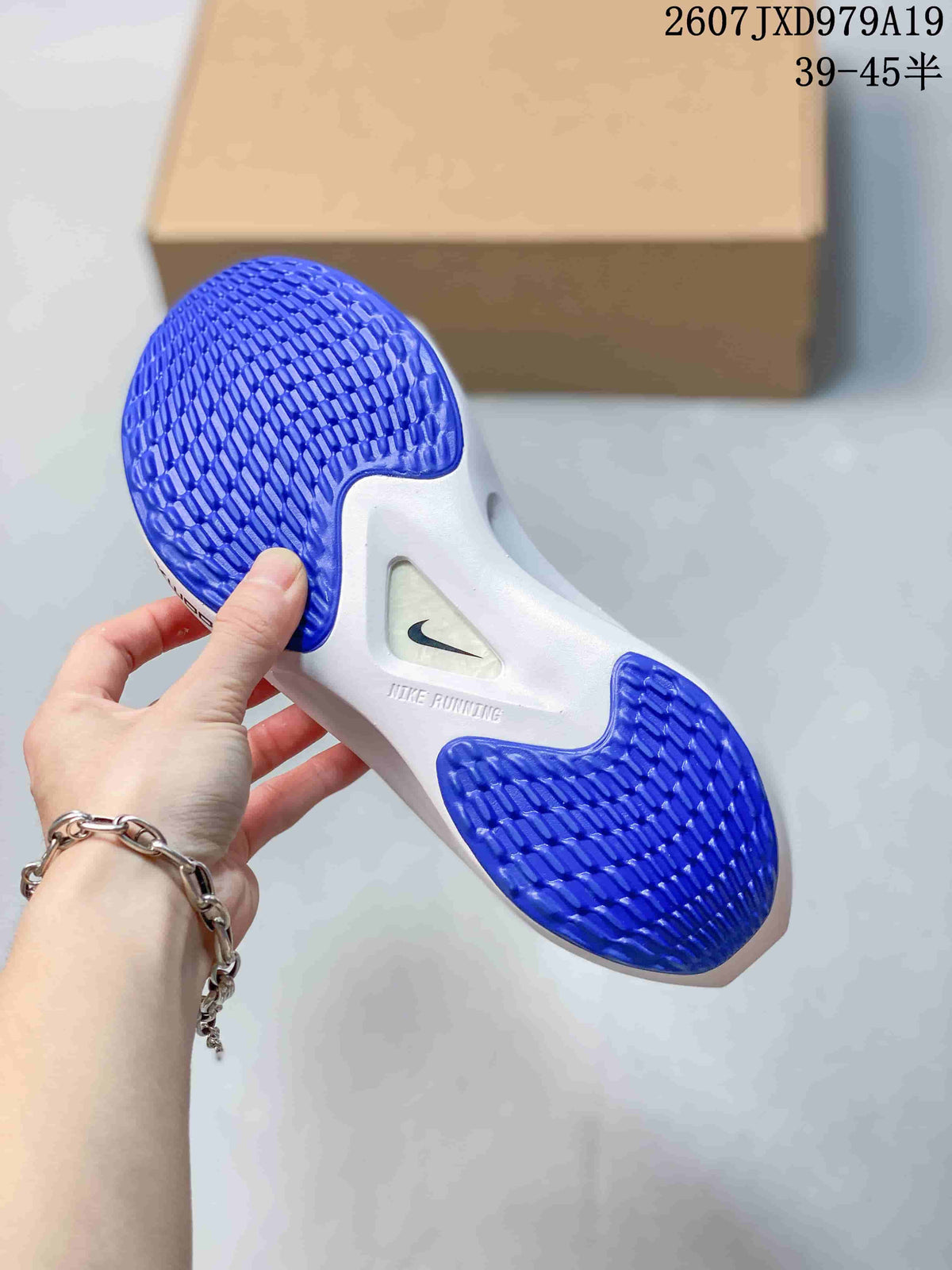 Underside view of a Nike running shoe showing blue patterned rubber outsole sections and a white midsole.