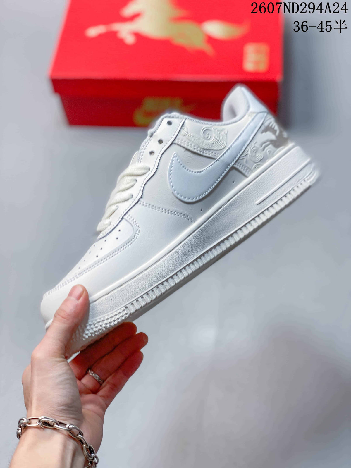 Side view of the white low-top sneaker showing the Swoosh, perforated panels, decorative embossed details and layered sole.
