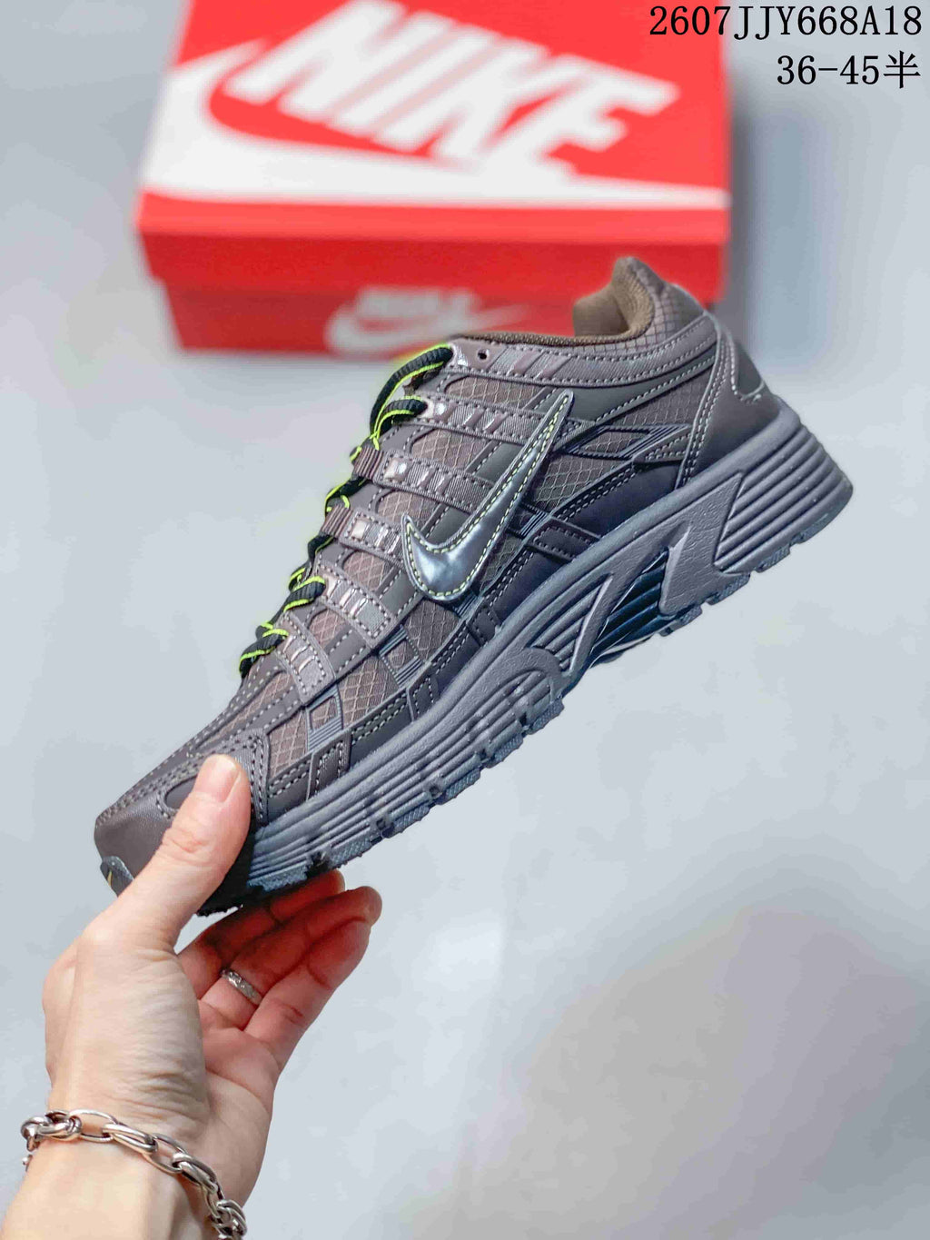 Side profile of a dark gray Nike P-6000 sneaker showing layered panels, side branding, and a textured midsole.
