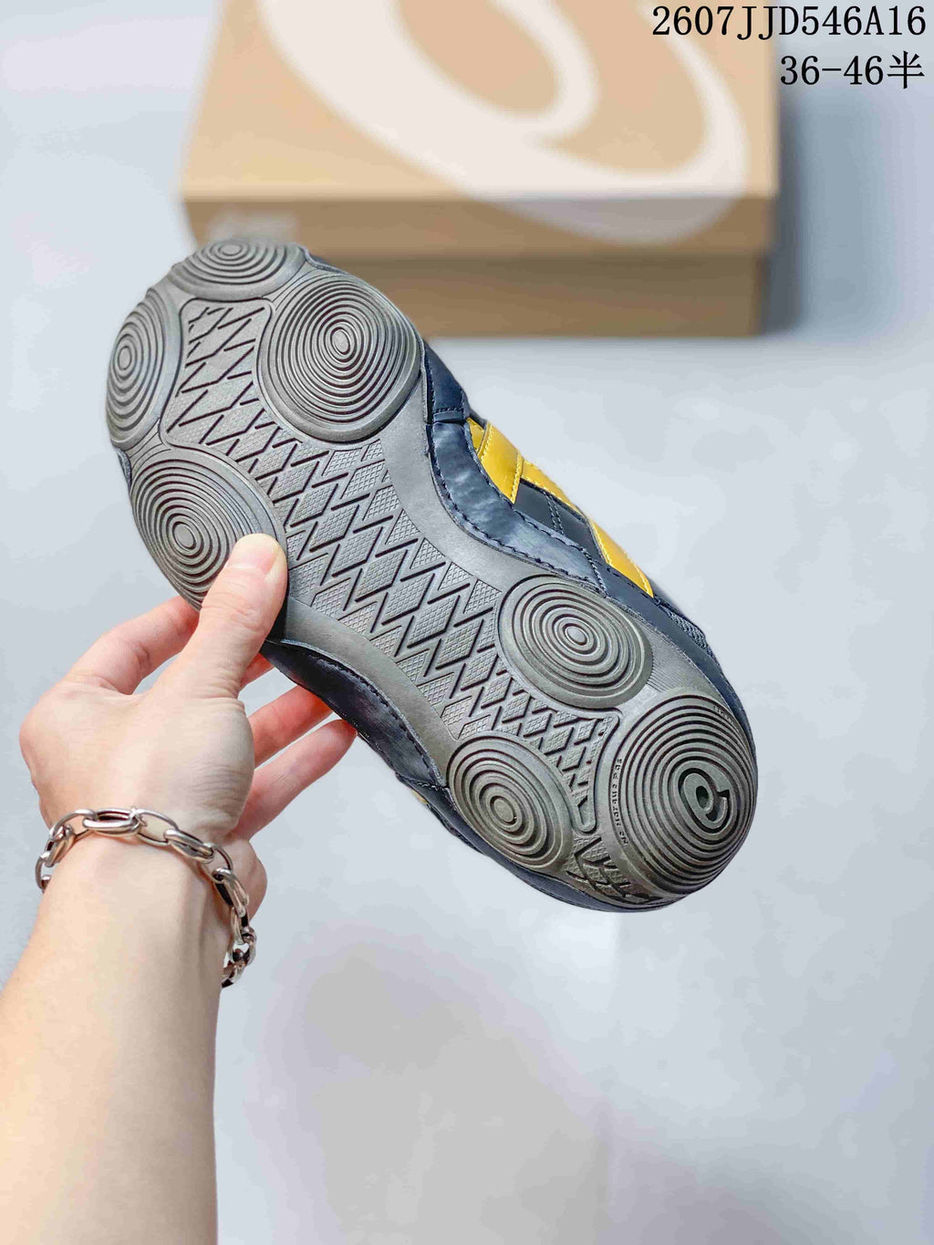 Underside of a navy and yellow ASICS sneaker showing the patterned rubber outsole and circular traction zones.