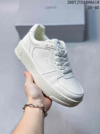 Close side view of an all-white SMFK sneaker showing the stitched upper, lace fastening, and side emblem.