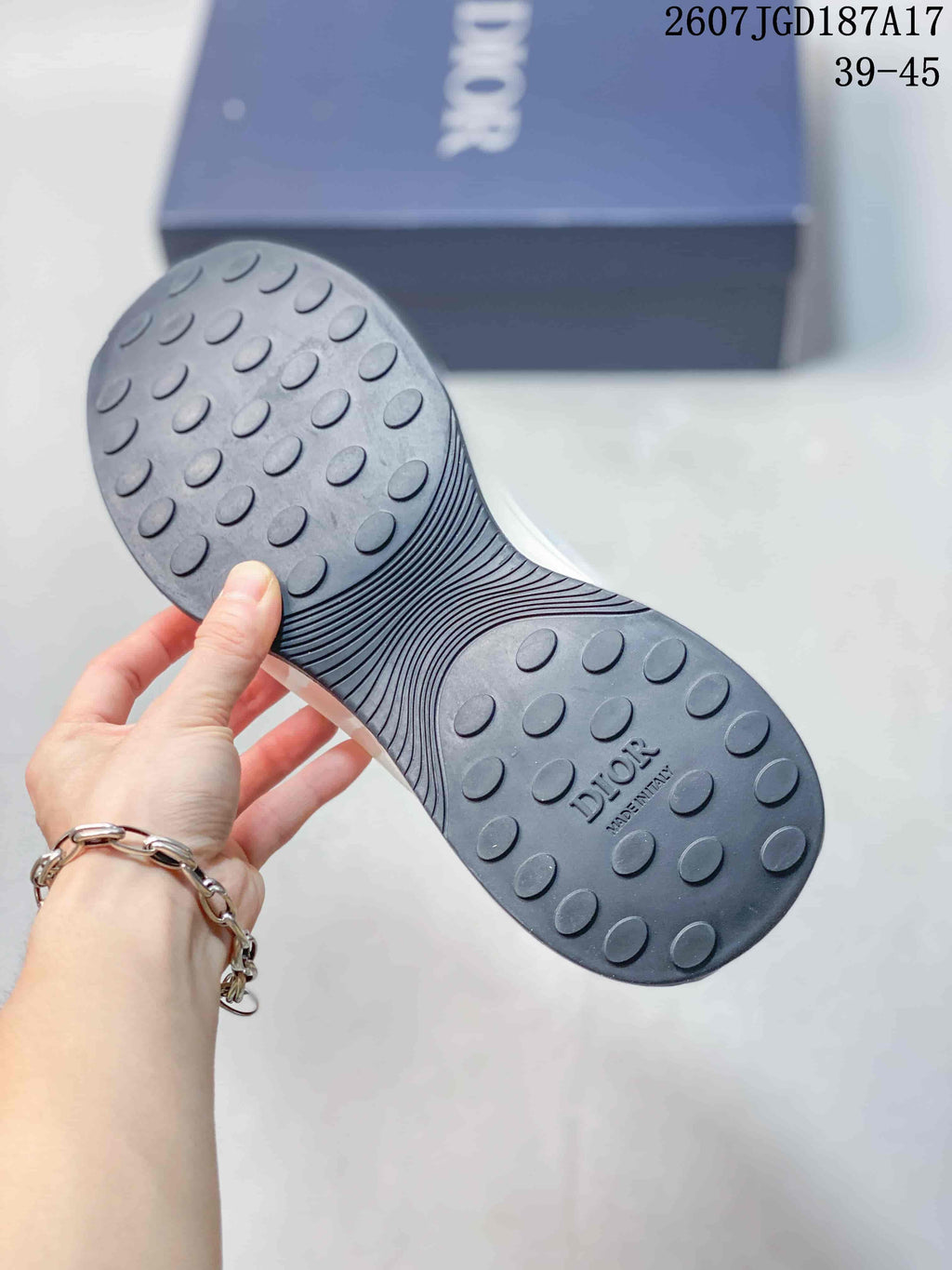 Close view of the dark textured rubber outsole with raised circular tread elements and Dior lettering.