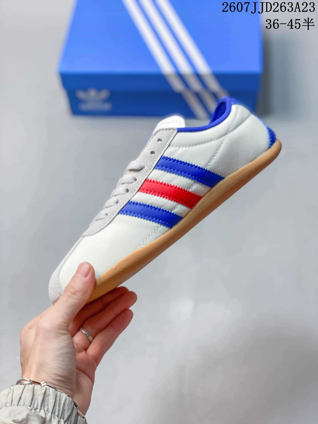Side profile showing the white low-top sneaker, blue and red stripes, and gum-colored outsole.