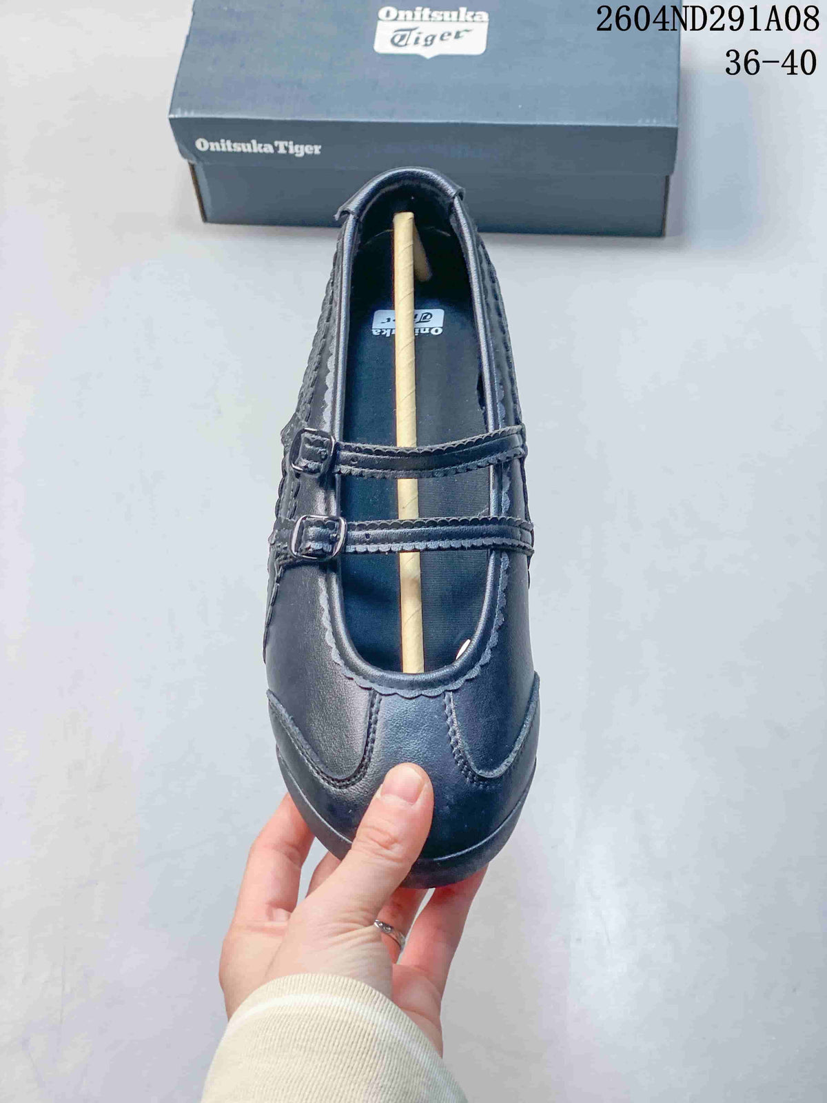 Top view of the black sneaker showing the rounded toe, two buckle straps, and stitched upper panels.