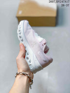 Side profile showing the pale pink textured upper, lace-up construction, and sculpted white outsole.