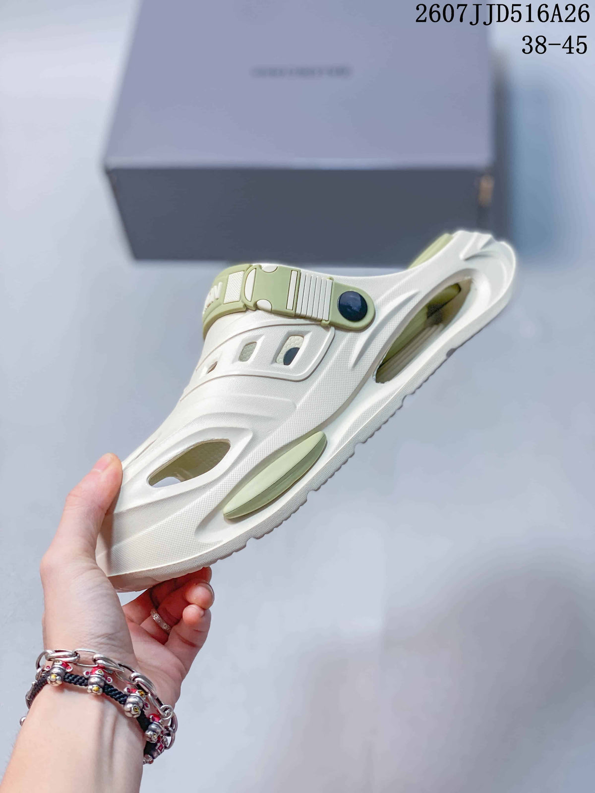 Side view of a white platform clog with ventilation openings, green side detailing and an adjustable heel strap.