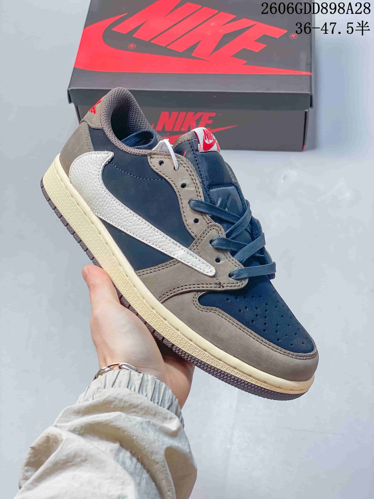Angled side view of the navy and taupe low-top sneaker with a light-colored reverse Swoosh