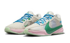 Pair of light-colored Nike basketball shoes with blue laces, a green Swoosh, and pink and green accents.