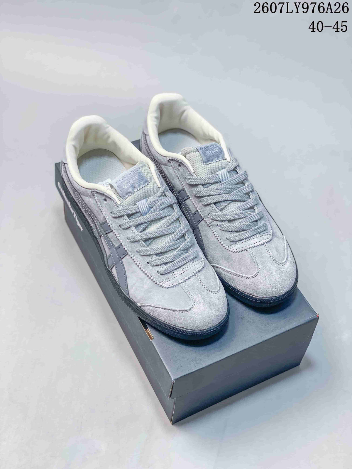 Light gray Onitsuka Tiger Tokuten sneakers with darker gray side stripes displayed on a shoebox.