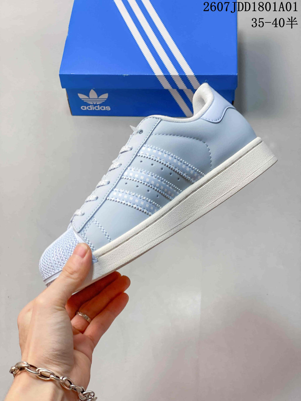 Side profile of the light blue Adidas Superstar sneaker with three stripes