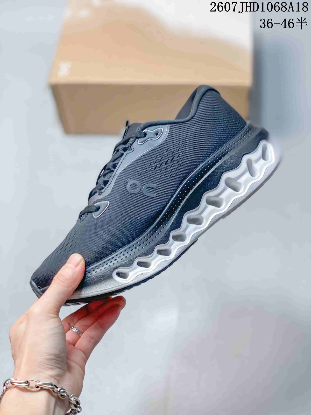 Side view of the dark gray sneaker showing the On logo, lace structure, and sculpted white midsole.