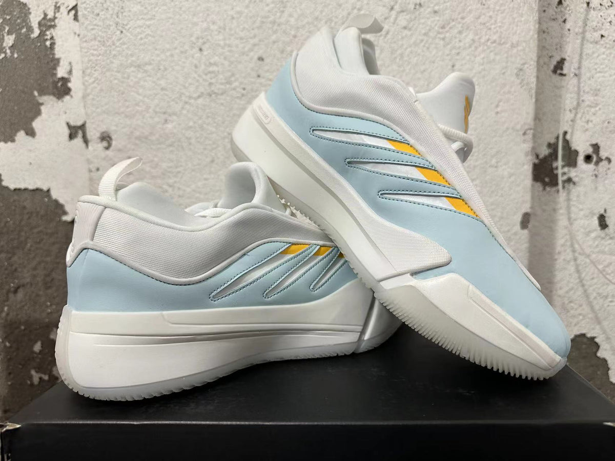 Pair of white, light blue, and yellow Adidas Dame 9 basketball shoes displayed together