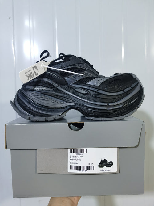 Dark grey and black 1011 sneaker shown on top of its box, with the box label visible.