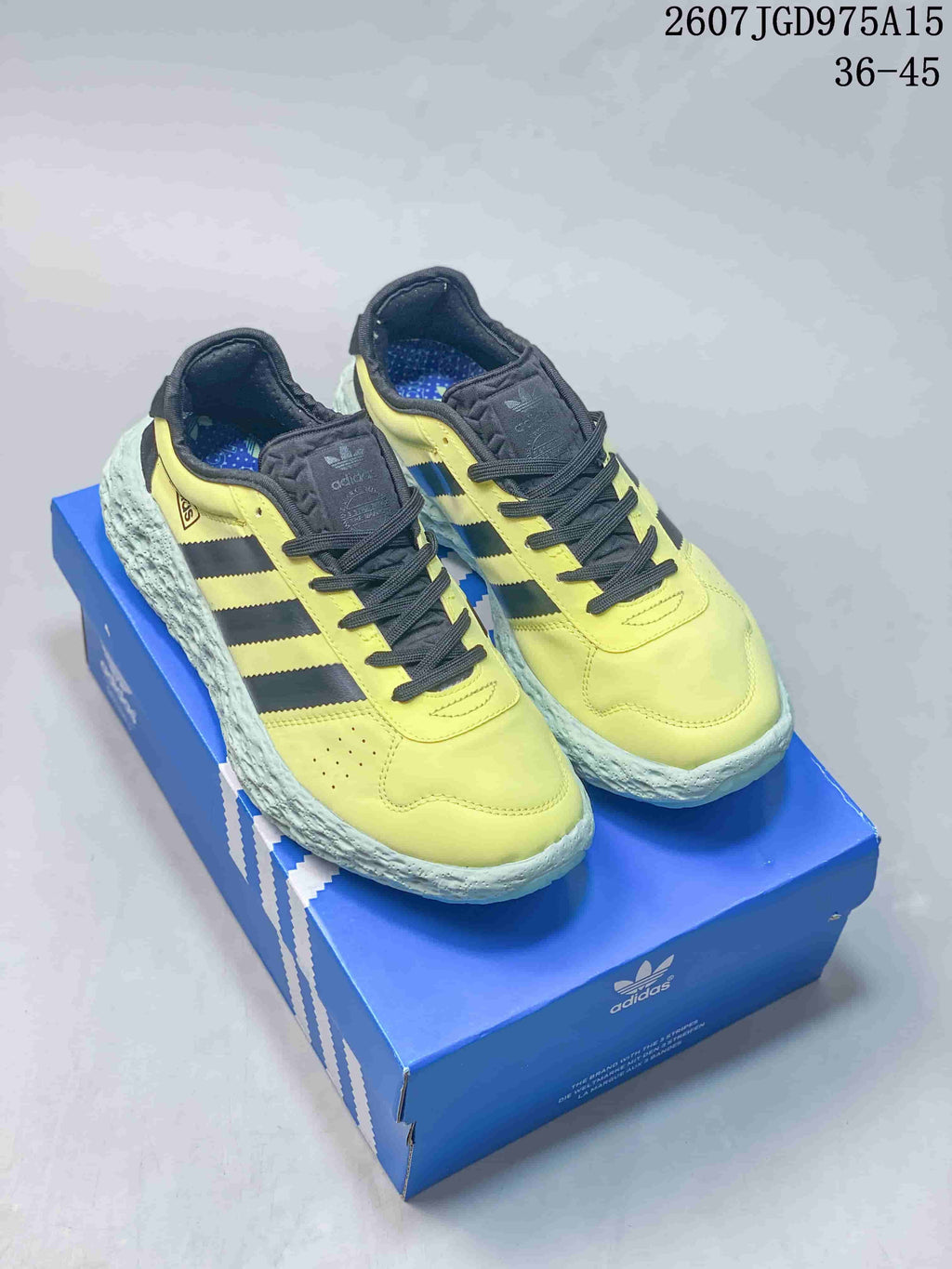 Pair of yellow and black Adidas Zponge low-top sneakers displayed on a blue Adidas shoe box.