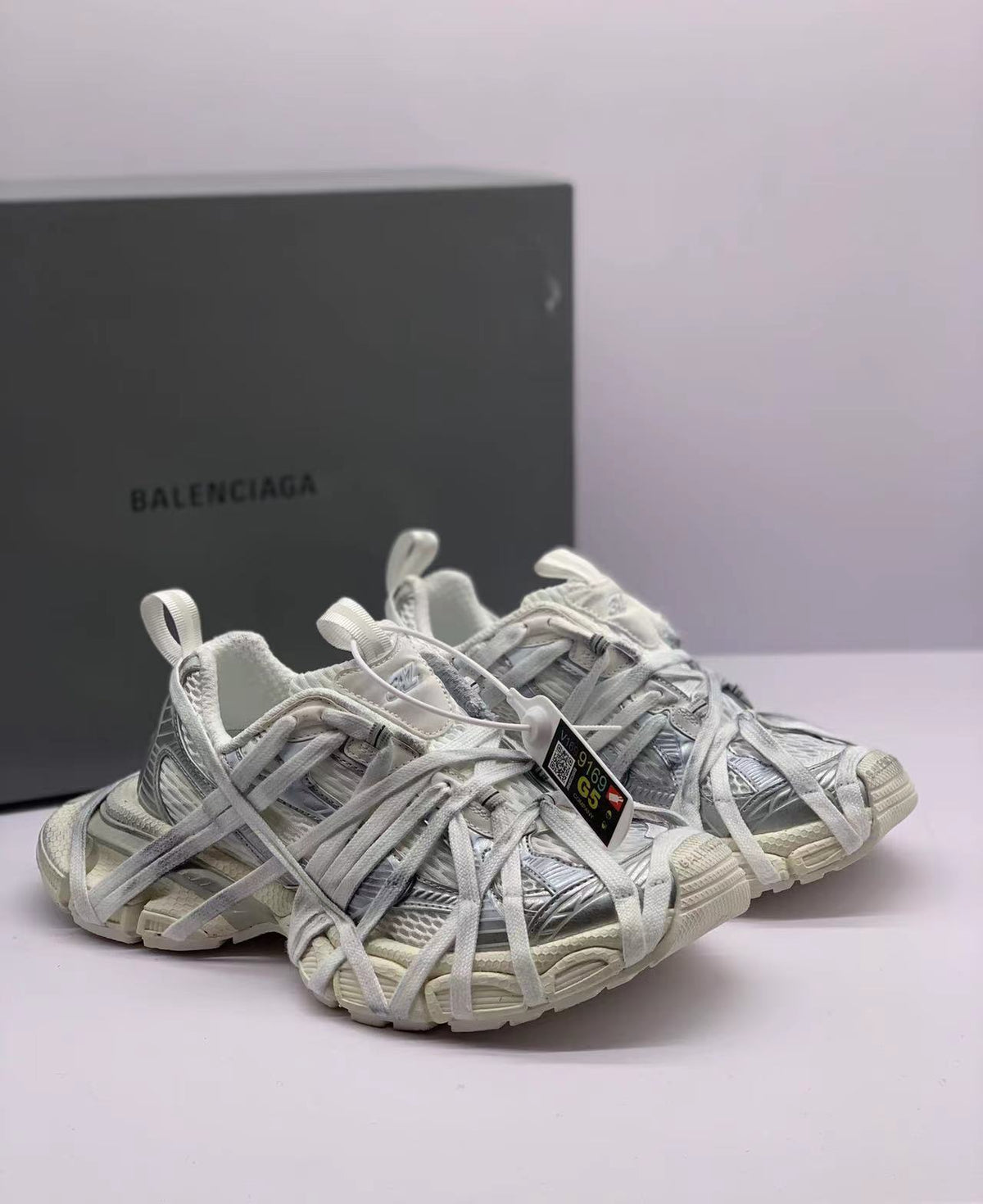 Three-quarter front view of the paired all-white sneakers with oversized layered laces.