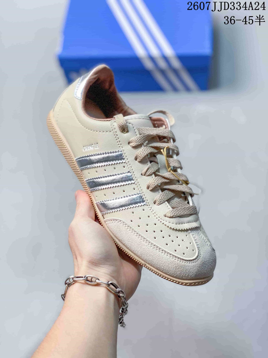 Angled side view highlighting the cream upper, silver stripes, perforations, and gum-colored sole.