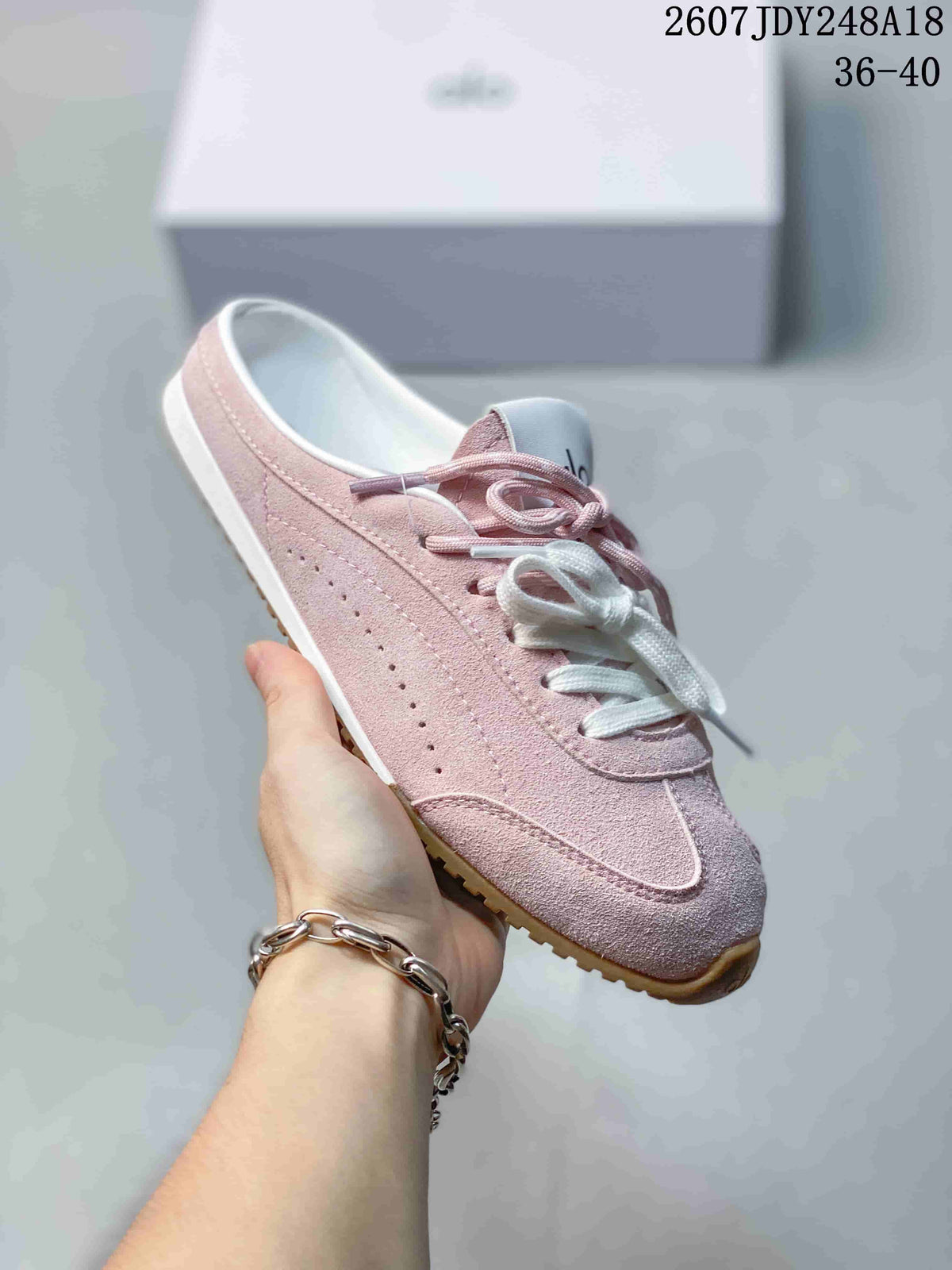 Side view of a pink alo mule sneaker showing the open heel, perforated side panel and gum-colored outsole.