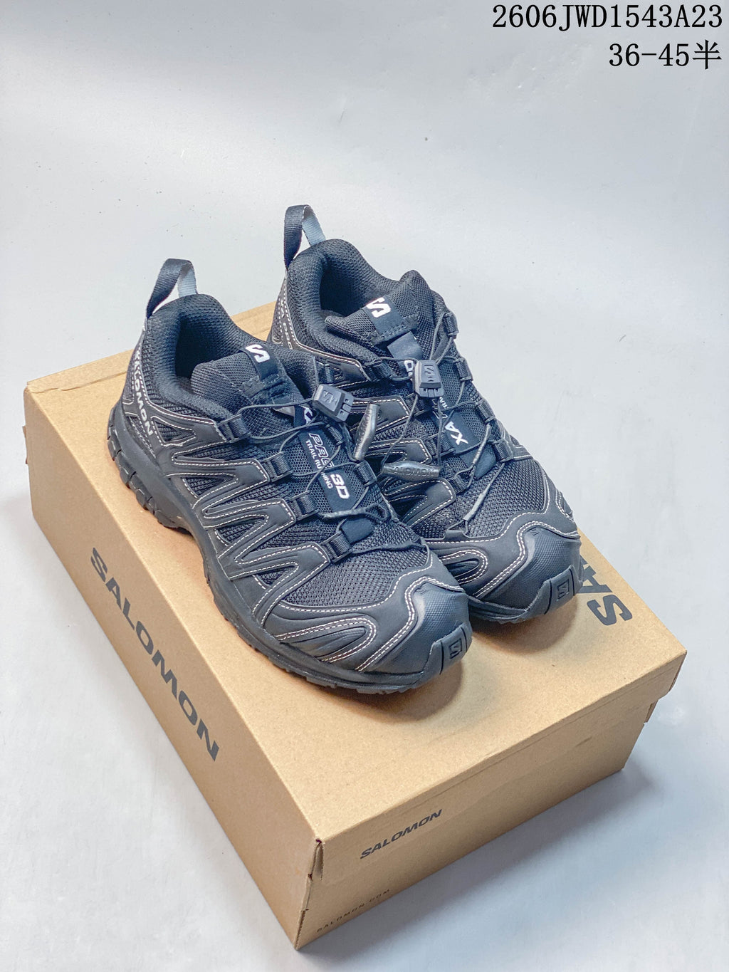 Pair of dark Salomon XA Pro 3D low-top shoes on a Salomon box; image overlay lists sizes 36–45.5.