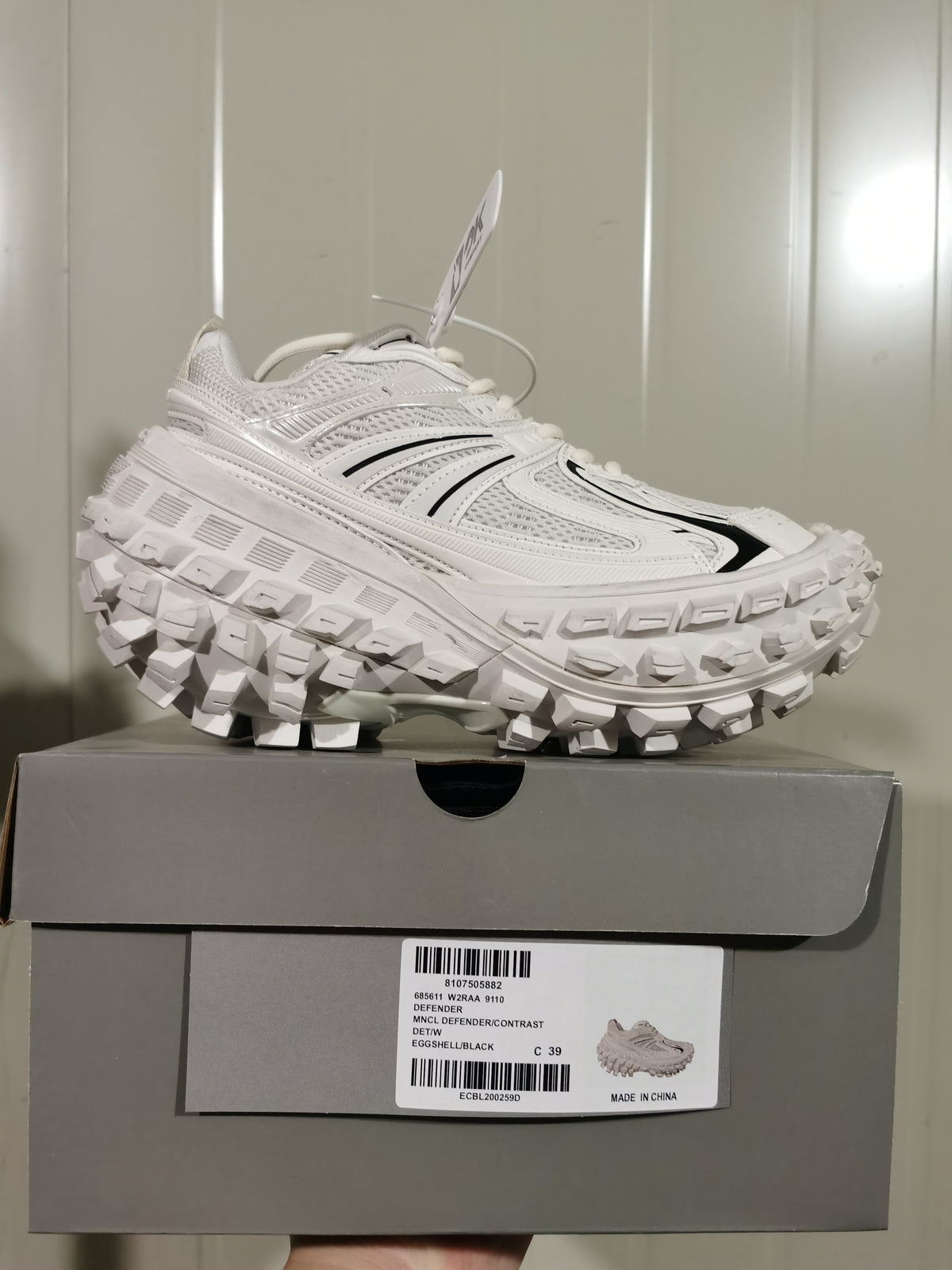 Side view of the sneaker resting on its box; the box label shows style 68561 W2RAA 9110, Eggshell/Black, and size C 39.