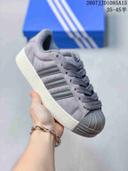Angled side view of the grey Adidas Superstar XLG sneaker showing the shell toe, side stripes, padded collar, and thick sole.