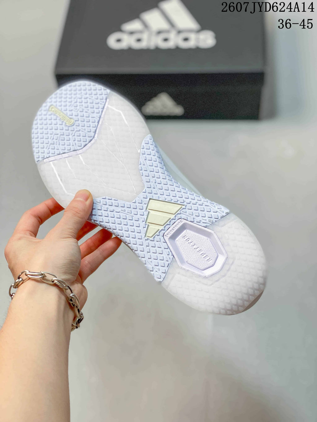 Underside view of a white training shoe showing its textured outsole pattern and central adidas detail.