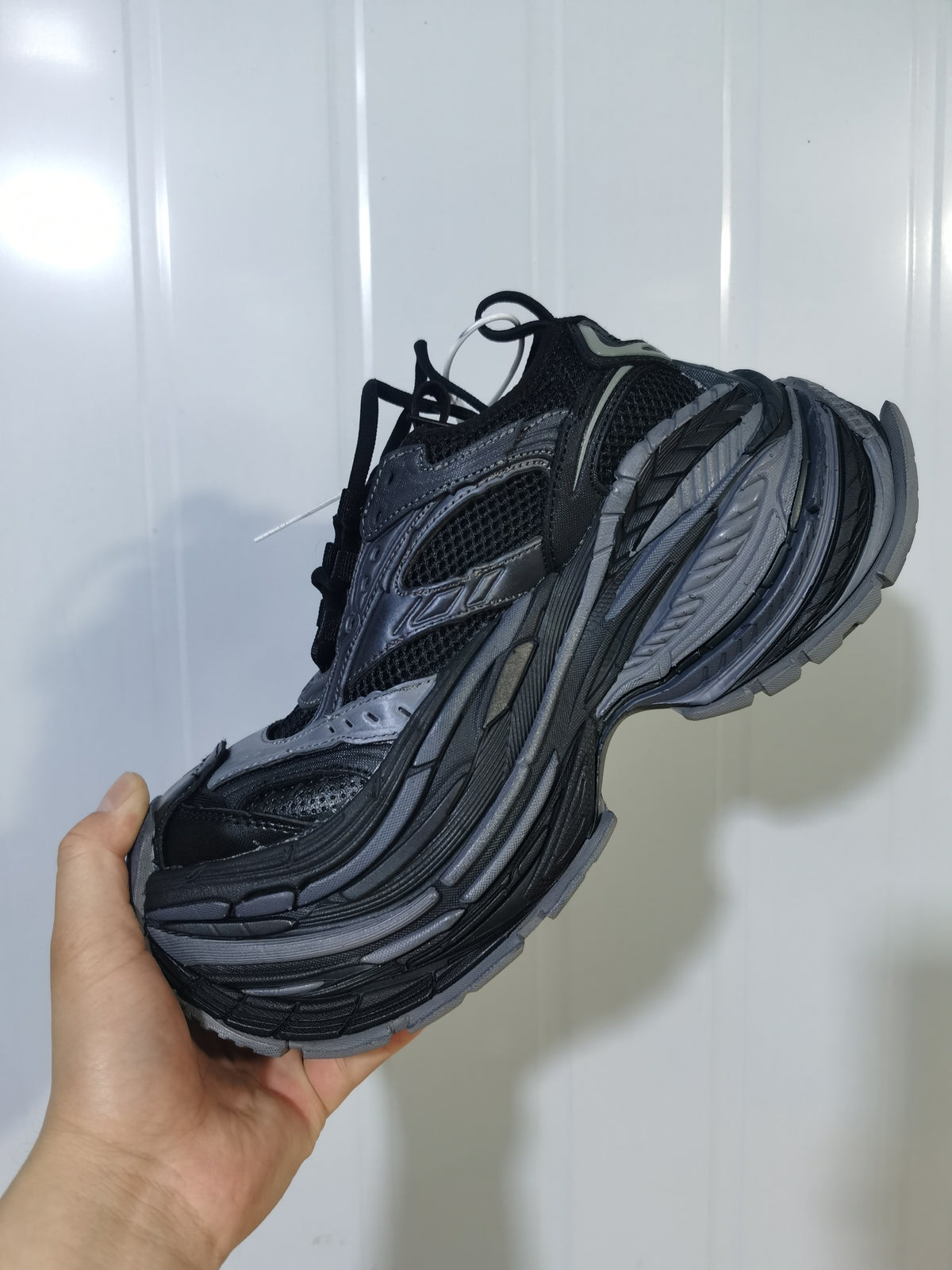Side view of the dark grey 1011 sneaker showing mesh panels, layered overlays and a sculpted sole.
