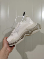Rear three-quarter view of the white sneaker showing mesh panels, tonal overlays, and the layered clear-look sole.