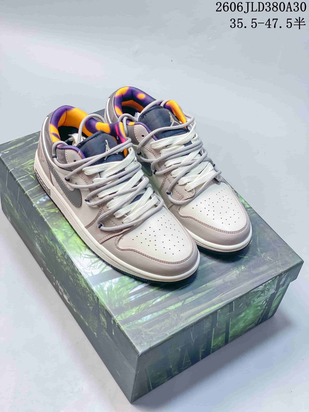 Pair of pink and gray low-top sneakers with purple and orange collar lining, displayed on a patterned shoe box.