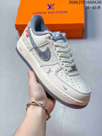 Angled view of a cream sneaker with gray accents and monogram-style pattern